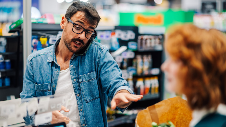 A man on the phone during checkout in a grocery store