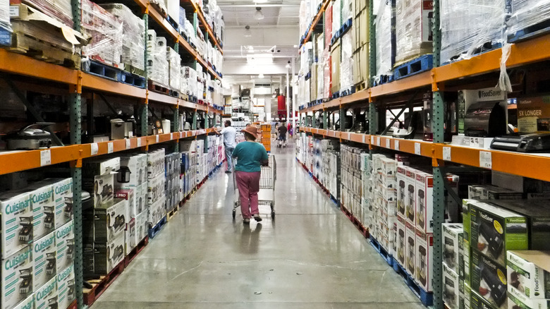 A woman pushing a cart strolls through an appliance aisle at Costco