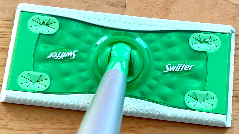 Metal pole going into a green Swiffer mop base.