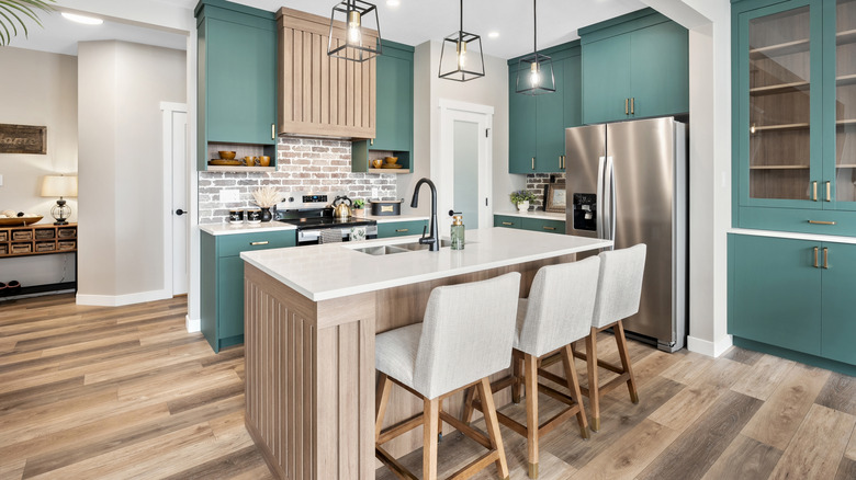 Kitchen with wood strip floors and green cabinets.