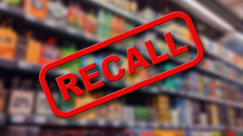 Blurry interior of a grocery store aisle behind large red Recall text