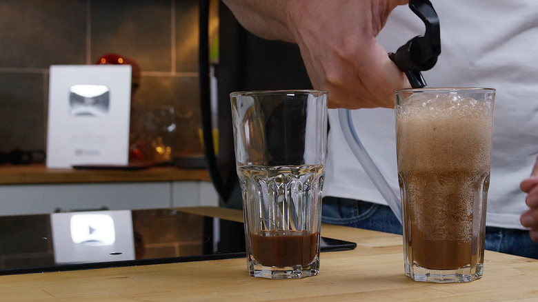 Soda being poured over ice in a glass
