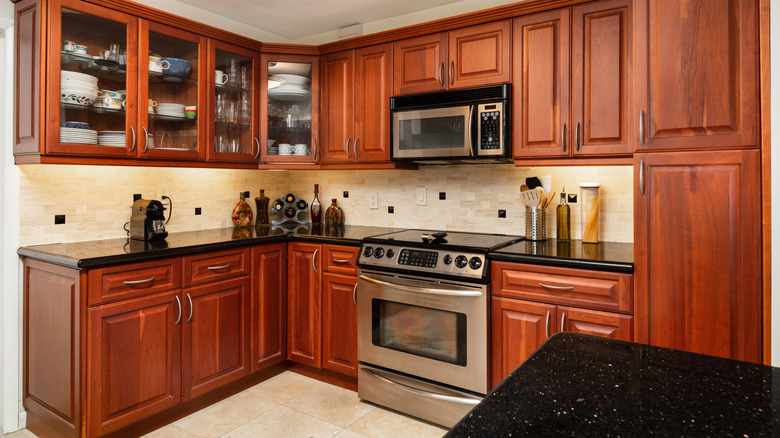 A dark cherry wood kitchen with dark countertops.