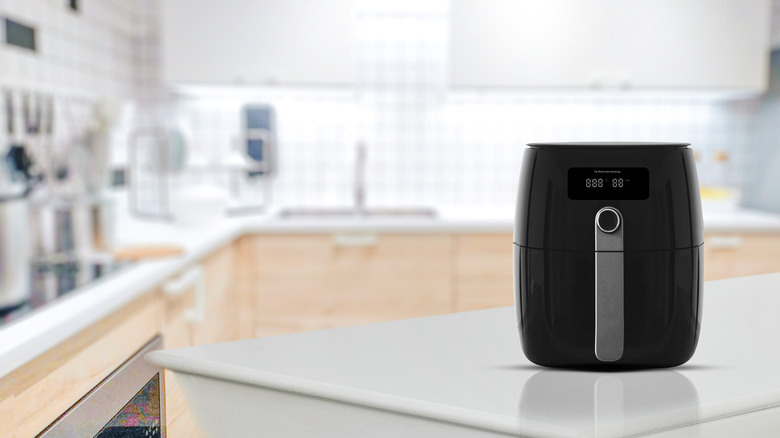 A black air fryer sits on a sleek countertop
