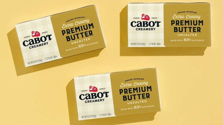 Slabs of Cabot Creamery Extra Creamy Premium Butter on a butter-yellow background.