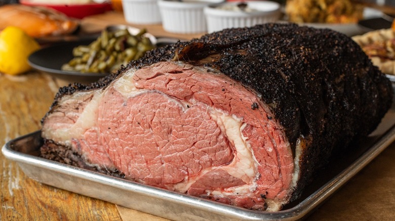 A smoked brisket from 4 rivers smokehouse restaurant is surrounded by sides like grilled green beans, stuffing, and pie