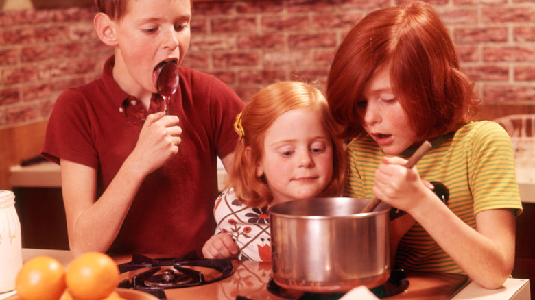 A group of kids cooking in a '70s kitchen.