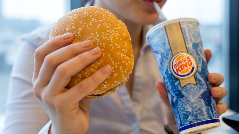 Person holding Burger King drink and burger