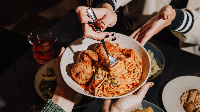 People sharing Dio Mio pasta with red sauce and meatballs