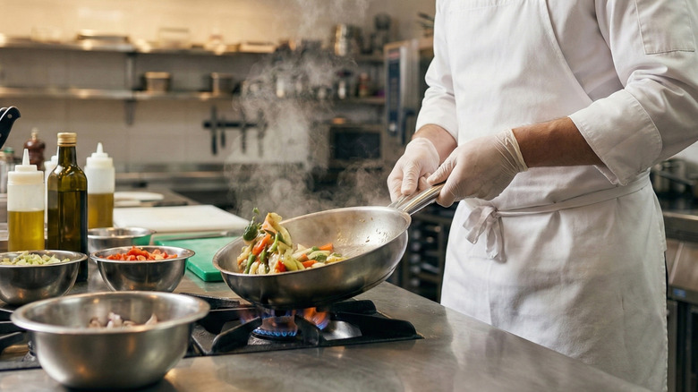 A chef cooking with a saute pan in a commercial kitchen.