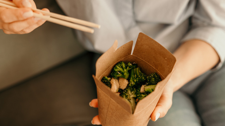 Person eating out of Chinese takeout container.