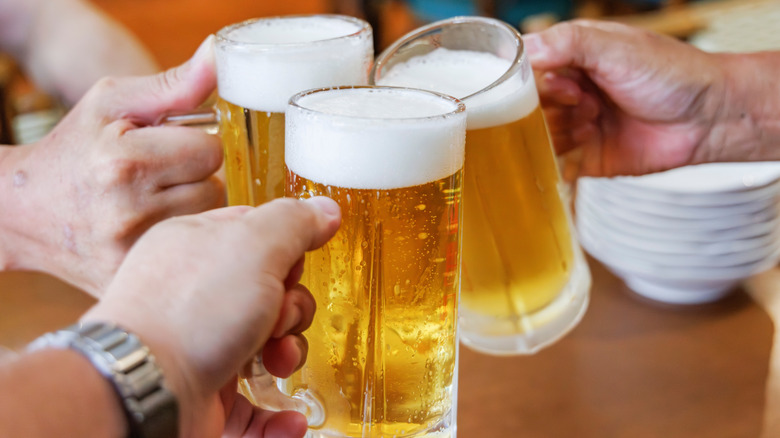 Customers cheering beer at bar.