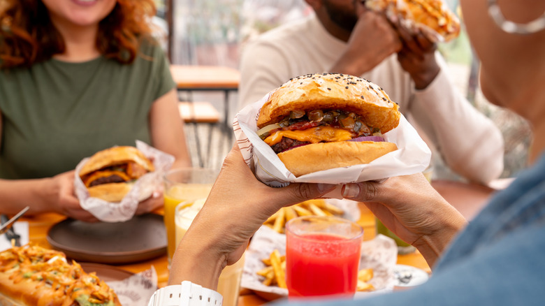 Friends happily eat burgers at a restaurant table
