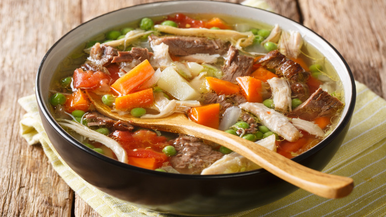 A wooden spoon rests in a bowl of booyah stew