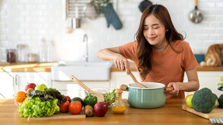 A happy cook prepares food in a stew pot in the kitchen