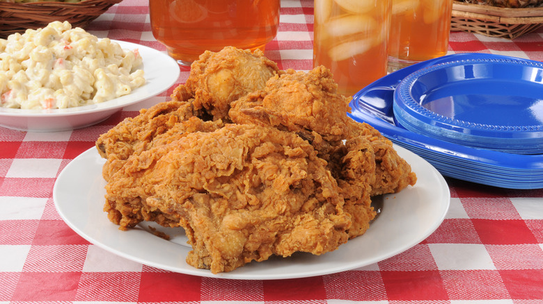 A plate of fried chicken on a red picnic cloth