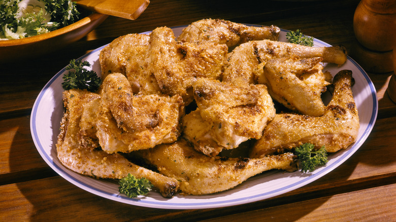 A plate of cold fried chicken on a picnic table