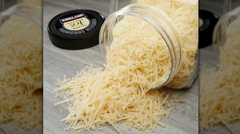 Kirkland's grated Parmigiano Reggiano cheese pouring out of jar onto table, wit the cap next to it.