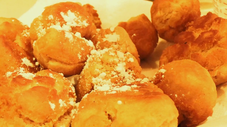A plate of bear sign donuts with a bit of powdered sugar on top.