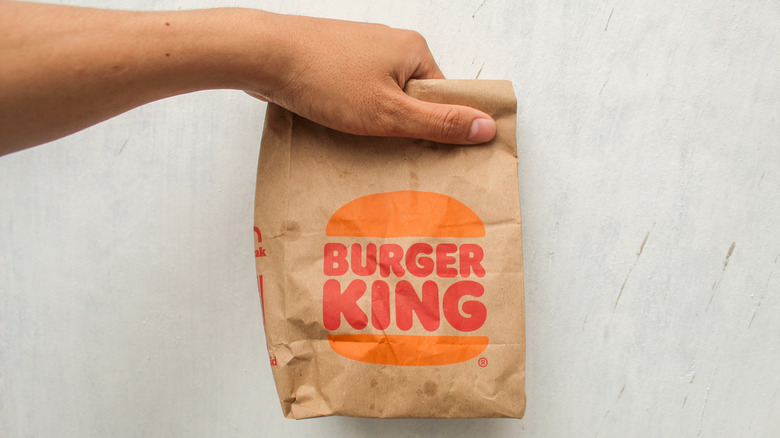 A person's hand holding a Burger King takeout bag.