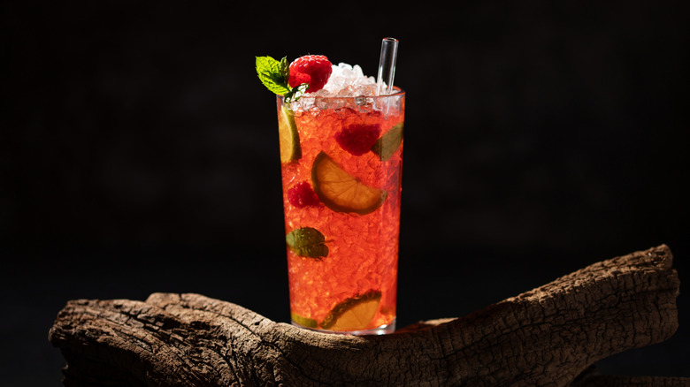 A raspberry and lime cocktail on a black background