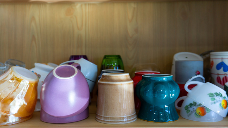 Colorful collection of coffee mugs stacked inside kitchen cabinet