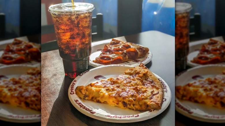 Two slices of pizza on Crosby's plates with a soda