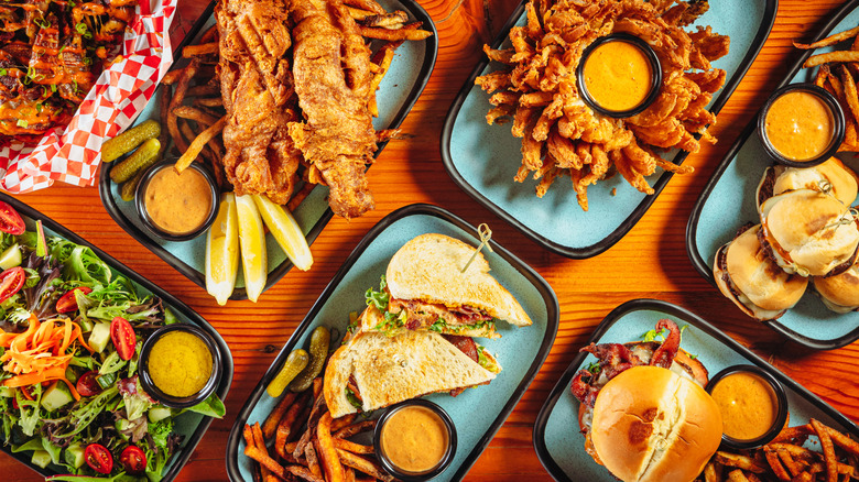 Various platters of game day foods with ramekins of spicy brown mustard at their centers