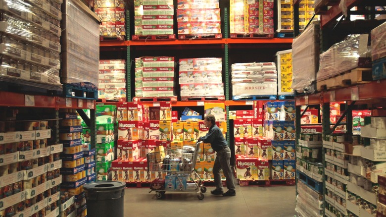 A lone shopper pushes a cart down a Costco aisle.