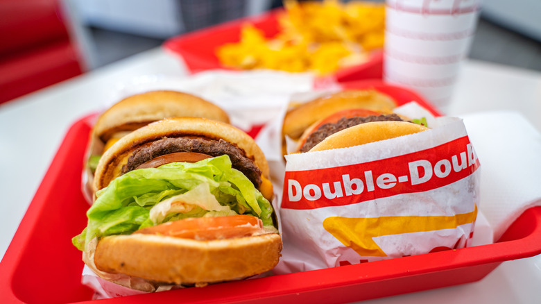 A tray full of Double-Double burgers alongside fries and a soda.