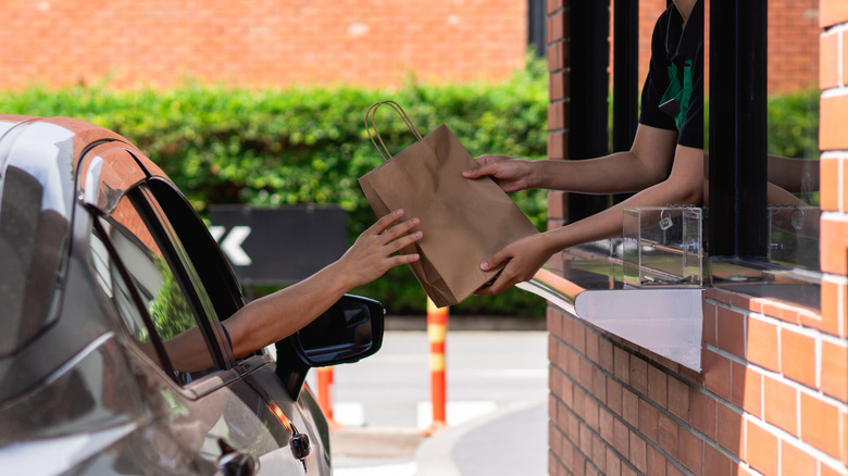 Someone grabs a bag of food from a drive thru.