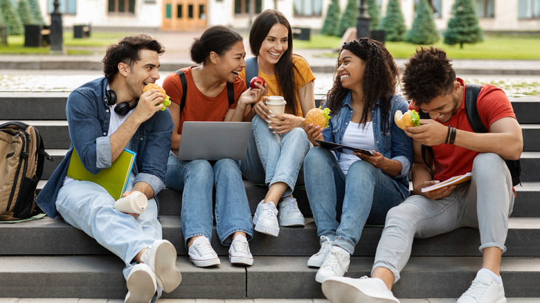 Young people sitting together on steps eating fast food