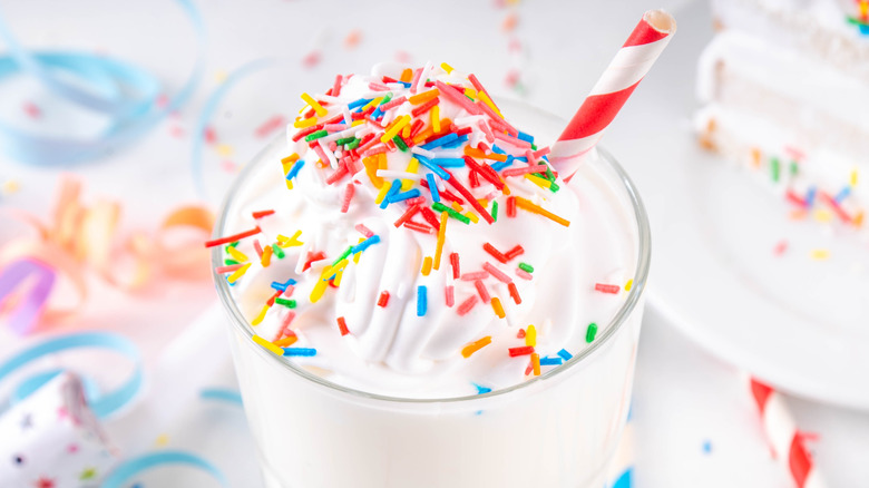 Vanilla milkshake with colored sprinkles and a red and white striped straw.
