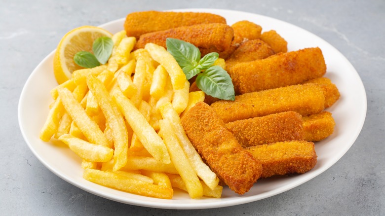 A plate of fish sticks and fries with lemon