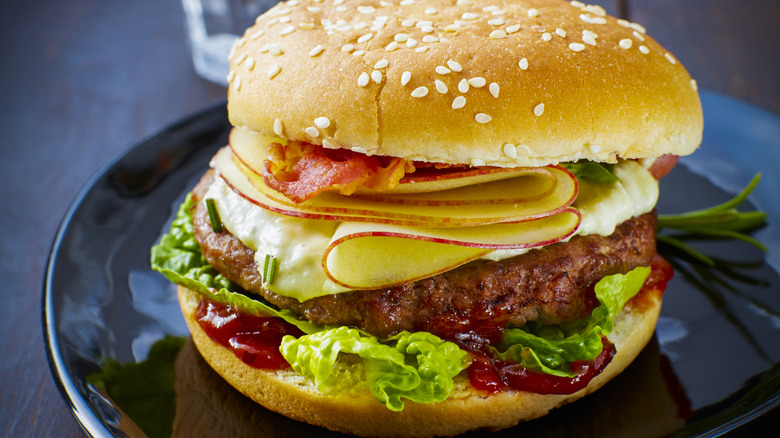 A burger topped with thinly sliced apples