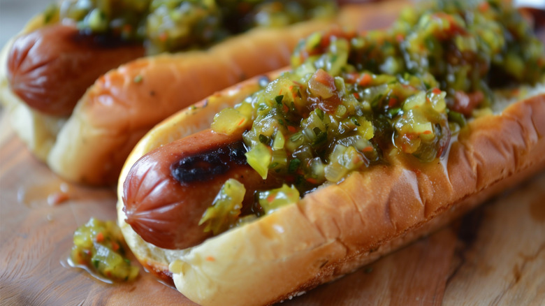 Two grilled hot dogs are topped with a generous helping of relish
