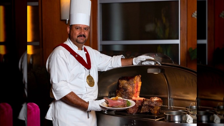 A meat carver at Lawry's holds open the metal cart.