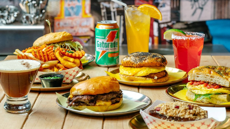 Various Odie B's sandwiches and drinks spread out on a wooden tabletop