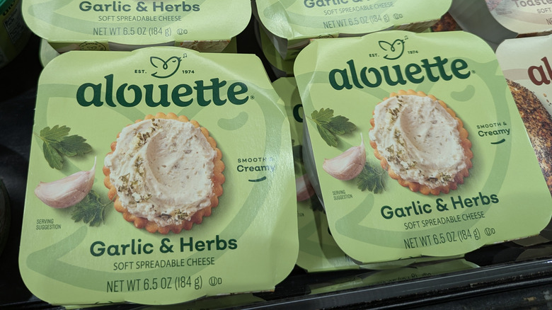 Packages of Alouette spreadable cheese sit in a supermarket cooler