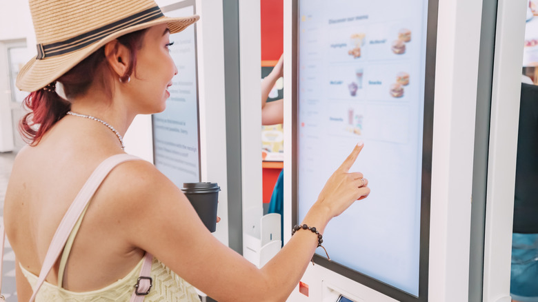 A customer studies a digital menu at a fast food restaurant