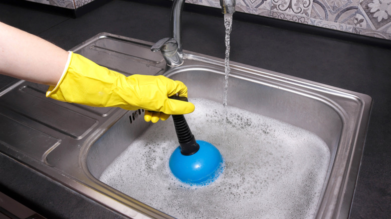 Person plunging a kitchen sink.