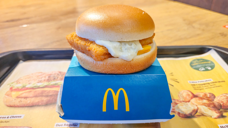 A McDonald's sandwich container with a Filet-O-Fish on top