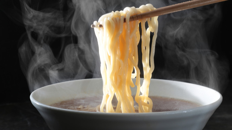 Chopsticks pulling ramen noodles from a bowl of broth