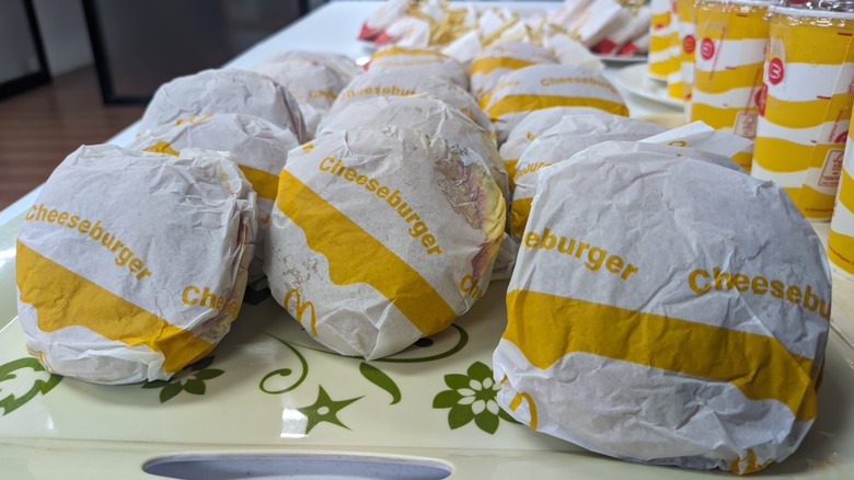 Many McDonald's cheeseburgers sit on a tray.