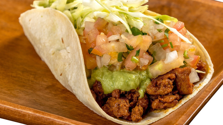 A Filiberto's taco sits on a wooden serving platter.