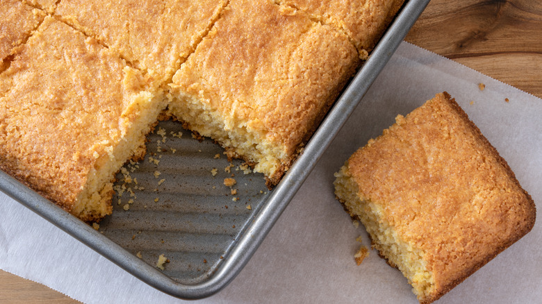 Cornbread sliced in a pan, with one piece off to the side