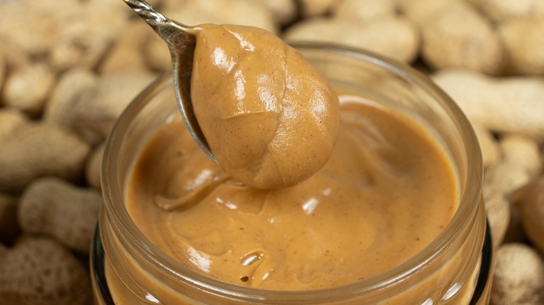 Closeup of a jar of peanut butter with a spoon in it