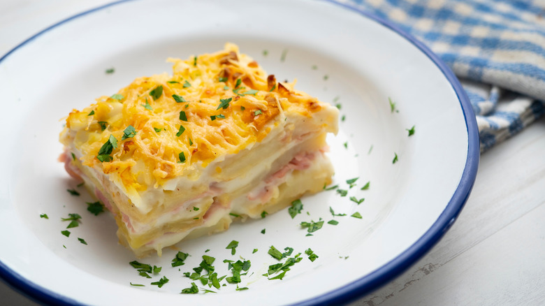 A slice of potato lasagna on a plate, garnished with herbs