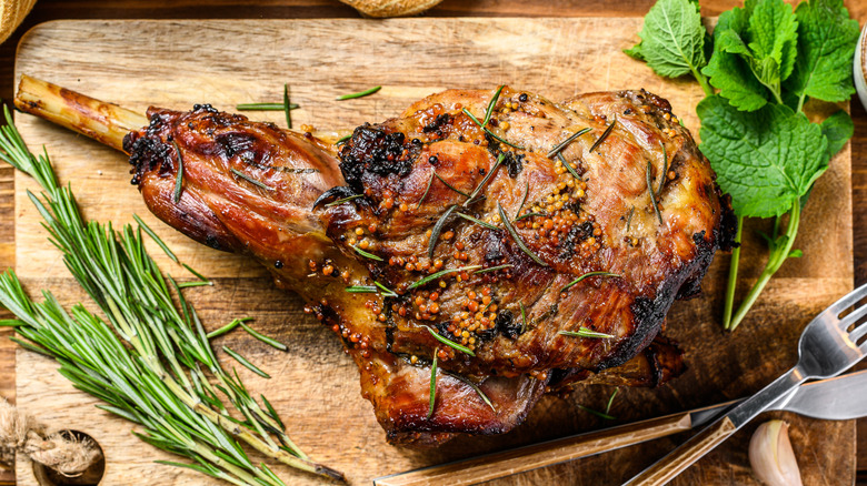 roasted goat leg is covered with fresh rosemary and mint