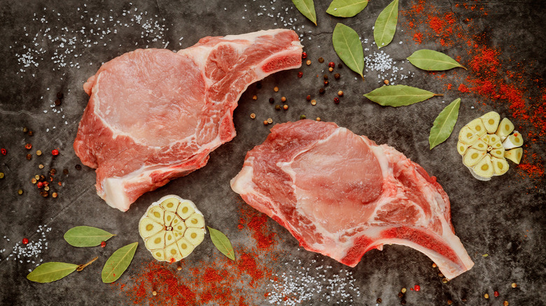 Two rib chops surrounded by garlic and herbs.